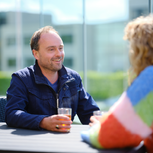 Foto van deelnemers op het balkon van het onderzoekscentrum met een glas drinken